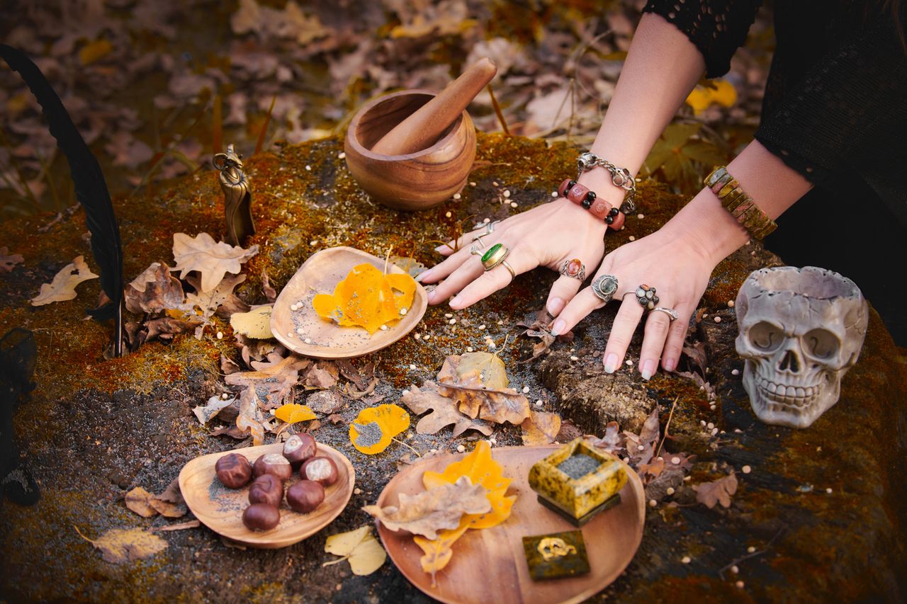 Atmospheric autumn ritual setup with hands, a skull, and natural elements on a mossy surface.