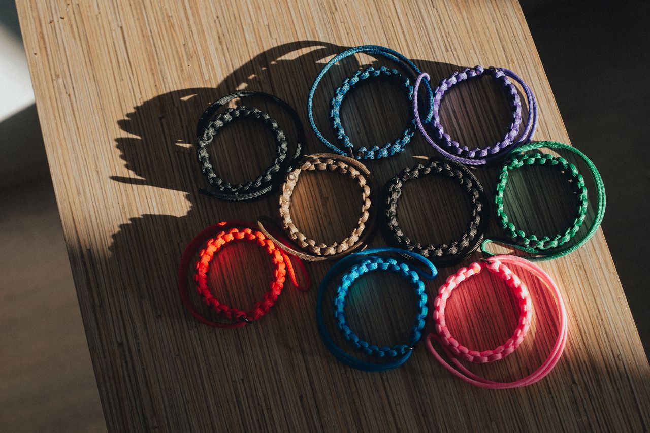 A vibrant array of handmade string bracelets displayed on a bamboo tray, captured from above.