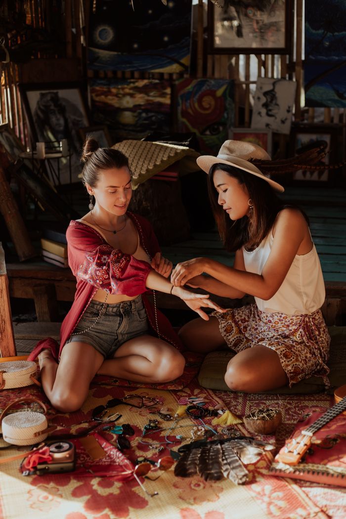 Two women making handmade jewelry in a cozy, artistic indoor setting, showcasing their creative process.