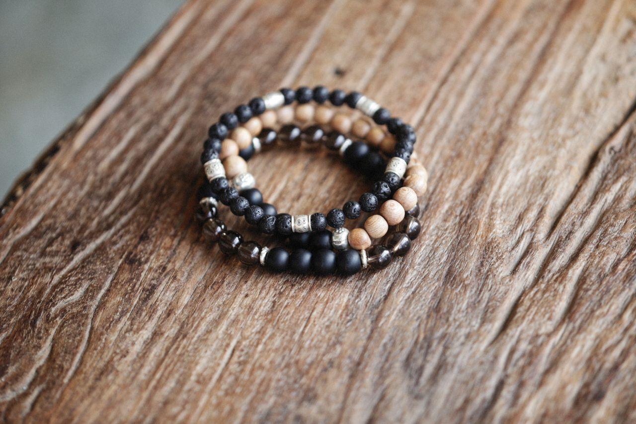Close-up of beaded bracelets in various colors and textures on a rustic wood surface.